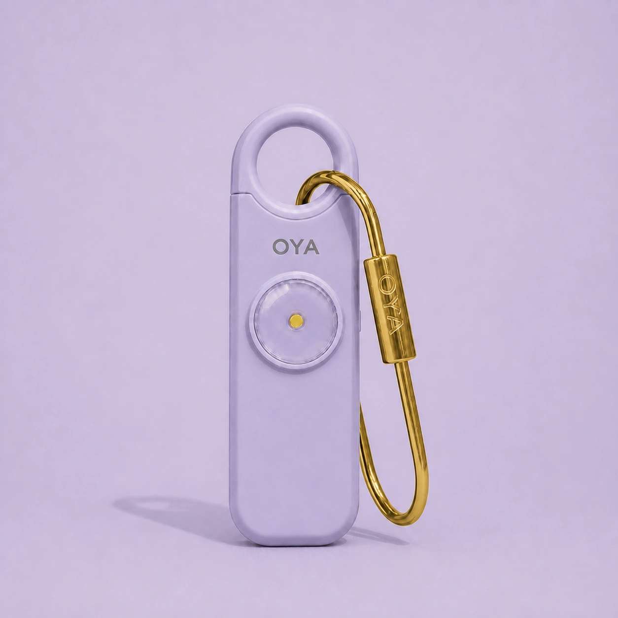 L’alarme personnelle OYA en Lilac Mist avec son clip doré, sur un fond assorti à la teinte