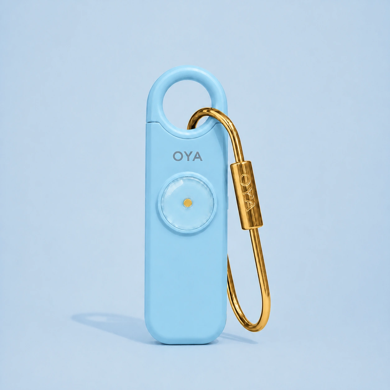 L’alarme personnelle OYA en Sky Blue avec son clip doré, sur un fond assorti à la teinte