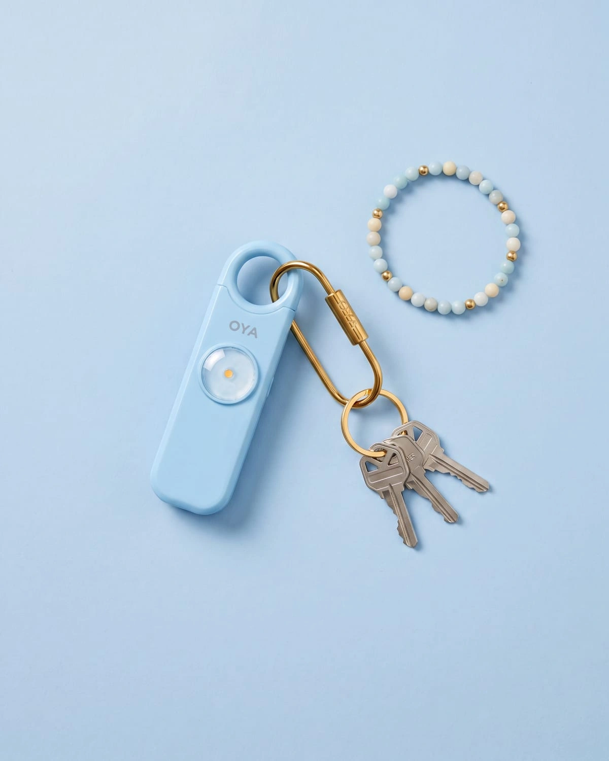 OYA Sky Blue, Anti-agression, sirène 130 dB et lampe, posée à plat avec des clés