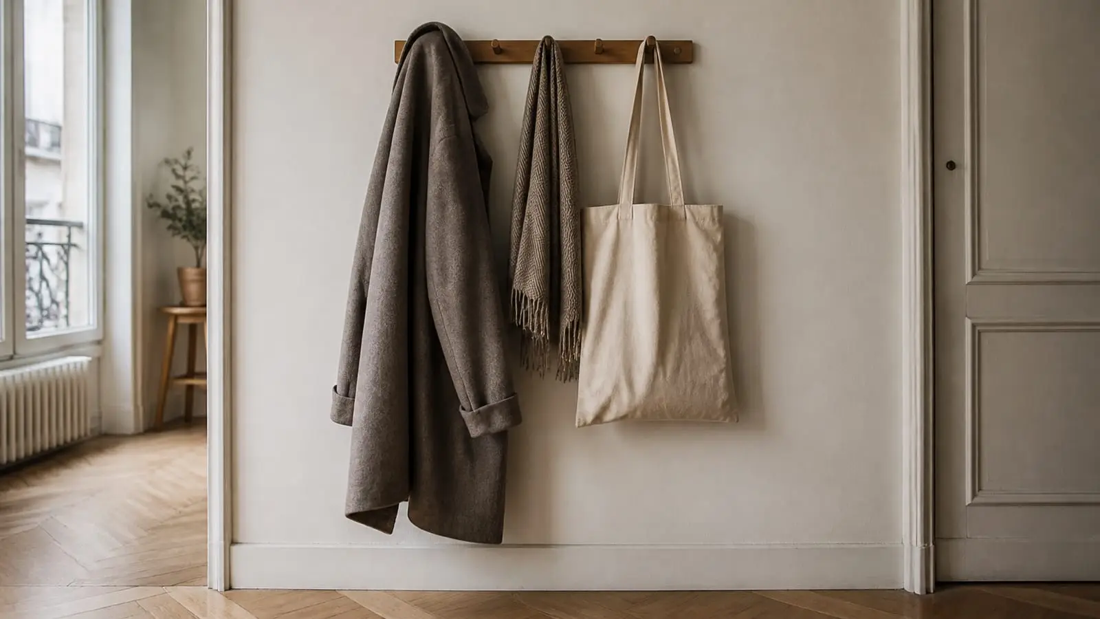 Un manteau de laine, une écharpe et un sac en toile accrochés dans une entrée.